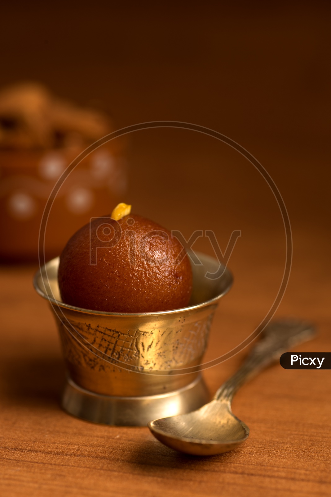 Indian Sweet or Dessert or Savoury Gulab Jamun  Served in an Elegant  Bowl with Spoon  On an Isolated Wooden Background