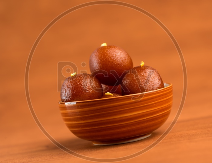 Indian Sweet or Dessert or Savoury Gulab Jamun  Served in a Wooden Bowl  On an Isolated Wooden Background