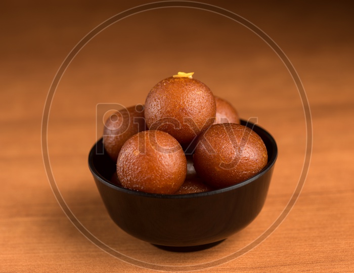Indian Sweet or Dessert or Savoury Gulab Jamun  in a Bowl On an Wooden Background