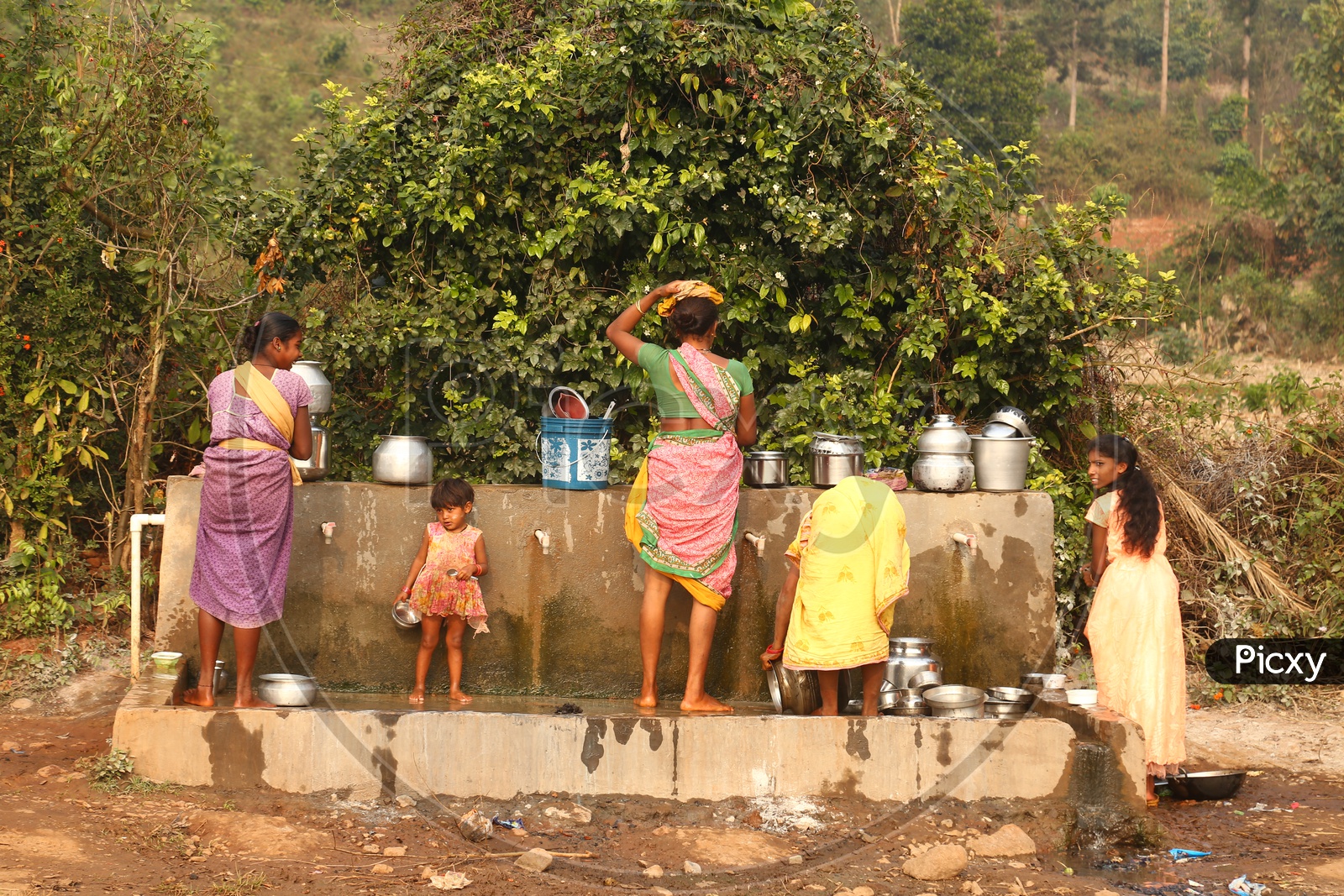 Tribals washing utensils at water taps.