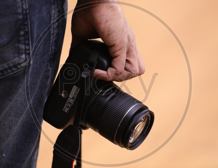 A Photographer Holding a DSLR Camera In Hand Closeup
