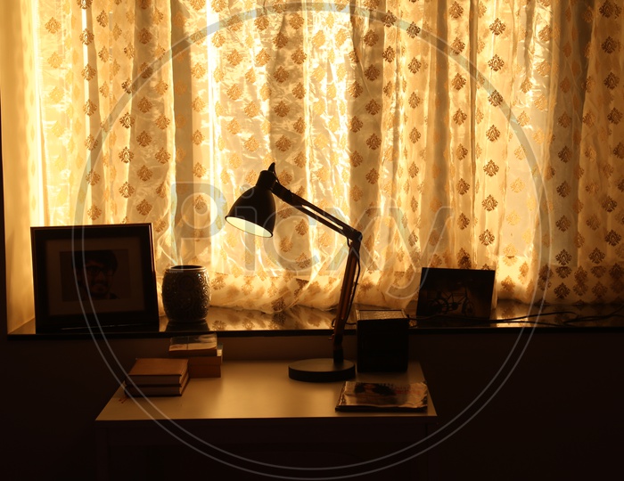 Reading Table With Books And Table Lamp  Near a Window  In a Bedroom