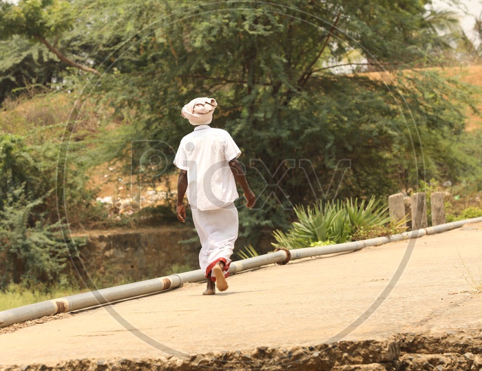 A Rural Indian Man Walking On a Bridge  in a Village