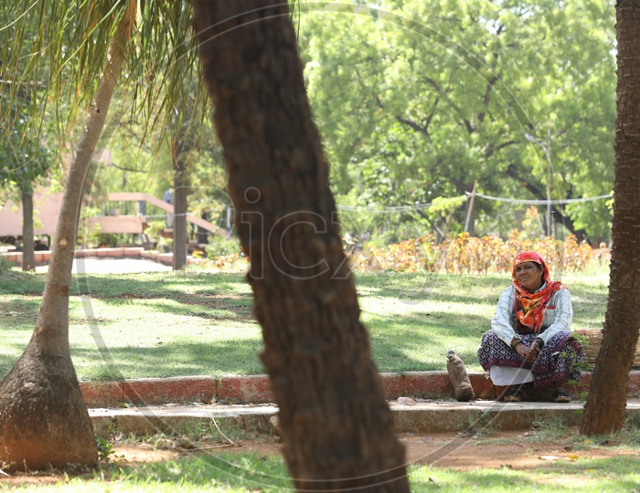 A Gardening Worker Sitting Or Taking Rest In a  Park By Sitting in Tree Shadow
