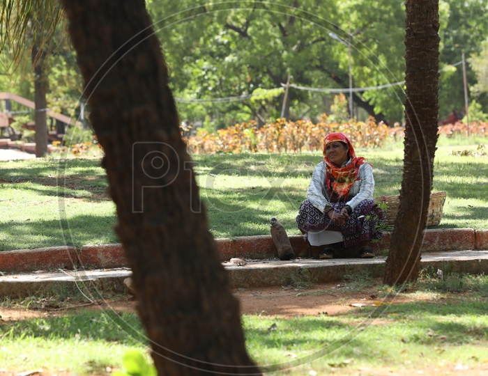 A Gardening Worker Sitting Or Taking Rest In a  Park By Sitting in Tree Shadow