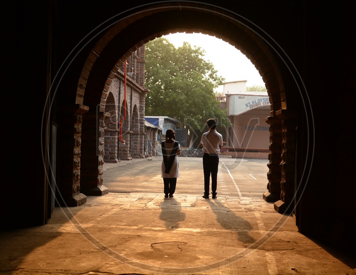 School Boy And Girl Standing In a Corridor Of a School Looking Intensely Towards Each other