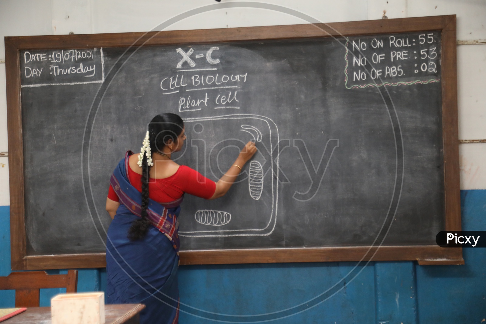 School teacher Writing On Blackboard In a Classroom