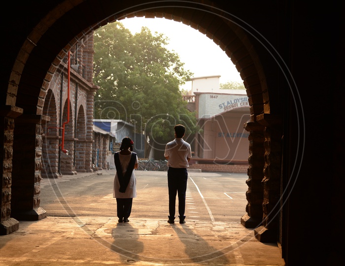 School Boy And Girl Standing In a Corridor Of a School Looking Intensely Towards Each other