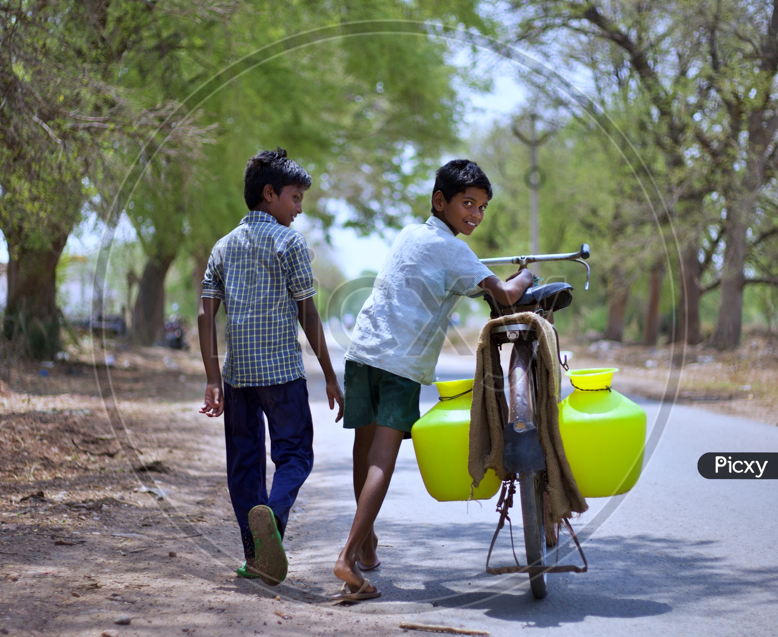 Kid carrying drinking water to home on a cycle.