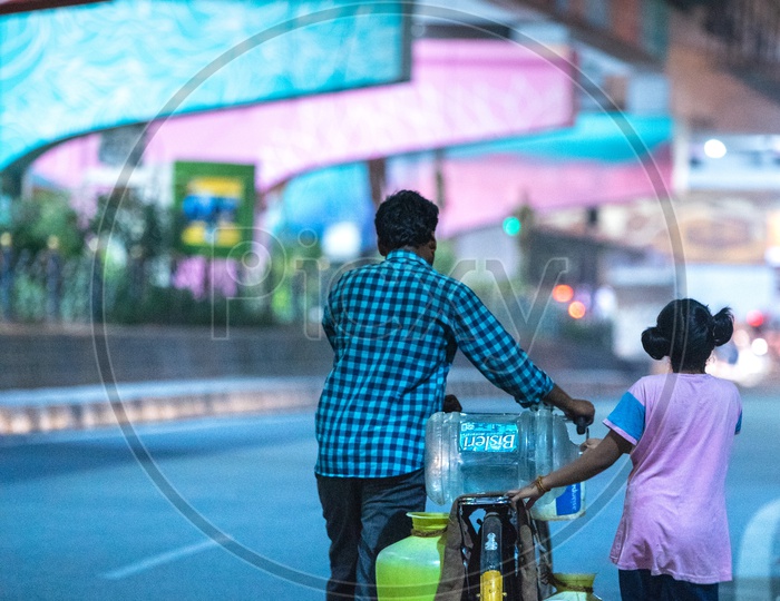 A Father And Daughter Carrying Water Vessels or Water Cans  In  Bicycle At Hitech City Roads In Hyderabad