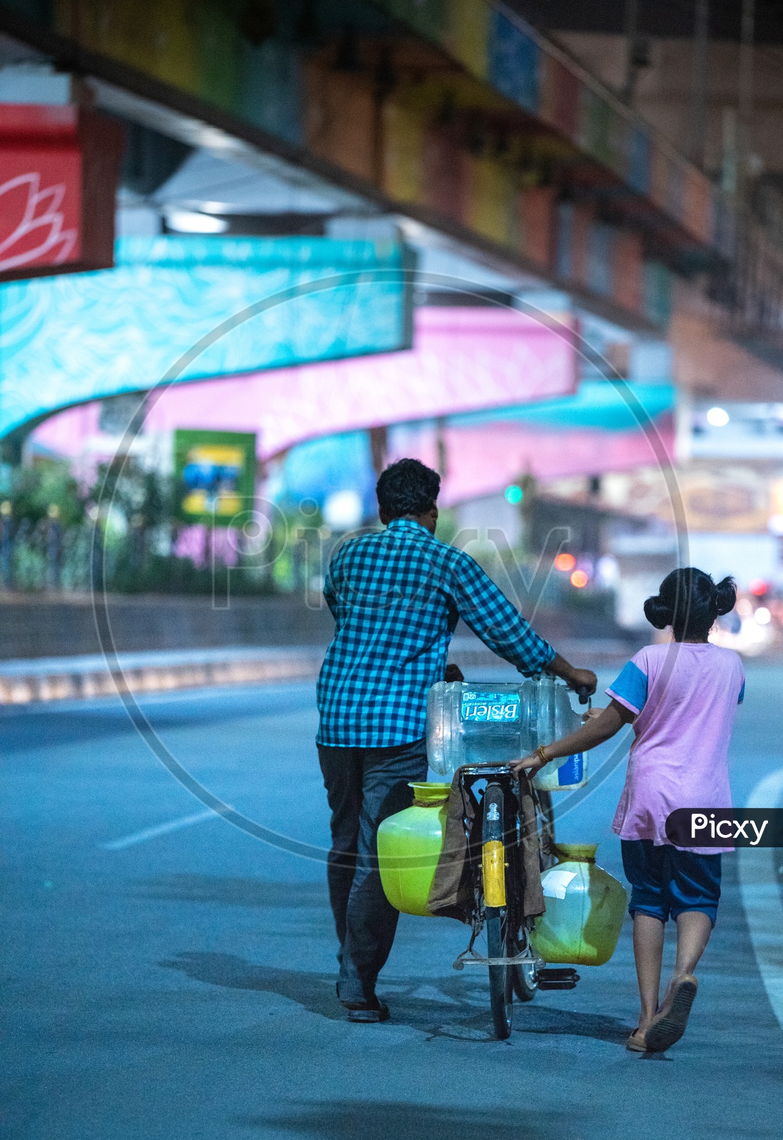 A Father And Daughter Carrying Water Vessels or Water Cans  In  Bicycle At Hitech City Roads In Hyderabad