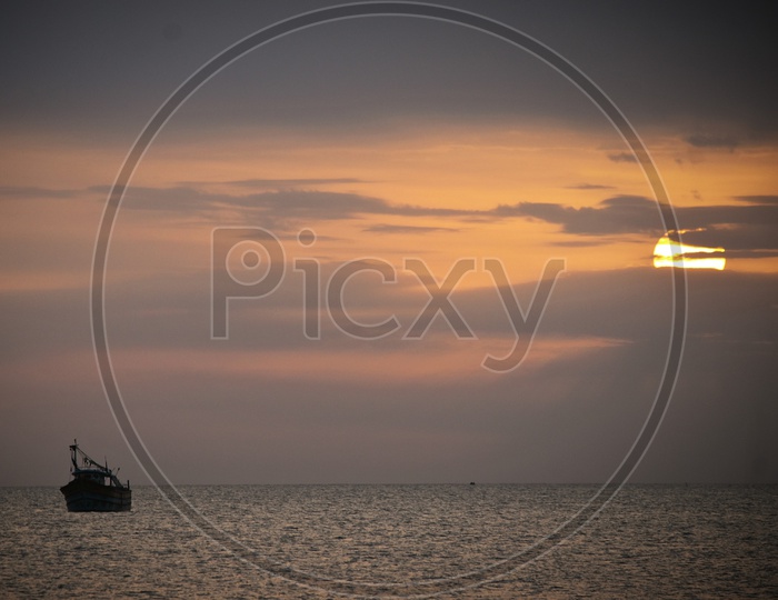 Silhouette Of Fishing Boats In Sea With A Sunset Sky in Background