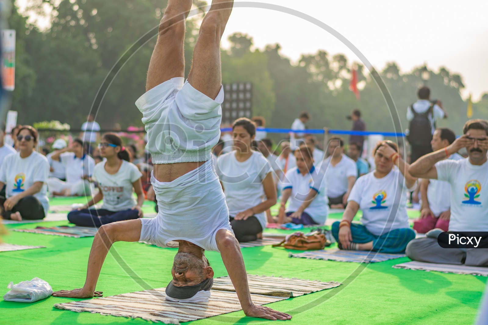 Man doing Sirsasana and others doing other yoga asanas on the fifth International Yoga Day 2019