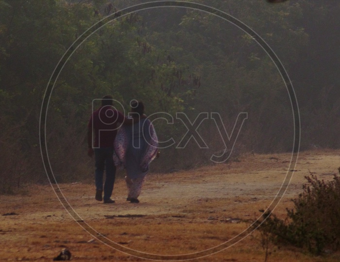A Couple Walking On a  Pathway  in a Foggy Morning  With Man Hand on Woman Shoulder
