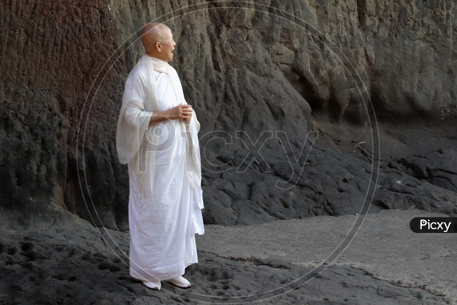 Image of A Buddhist Monk In White Dress At Stone Carved Ancient