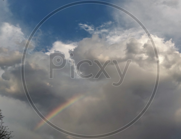 Rainbow in Sky With Cotton Clouds