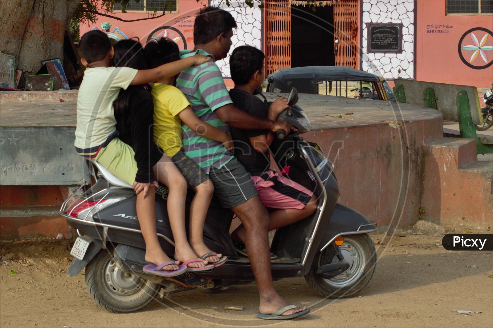 A Man Riding Scooty or Moped With Four Children along With Him