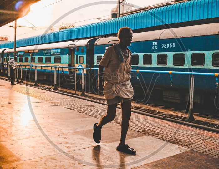 An Old Man Walking on a Railway Station Platform