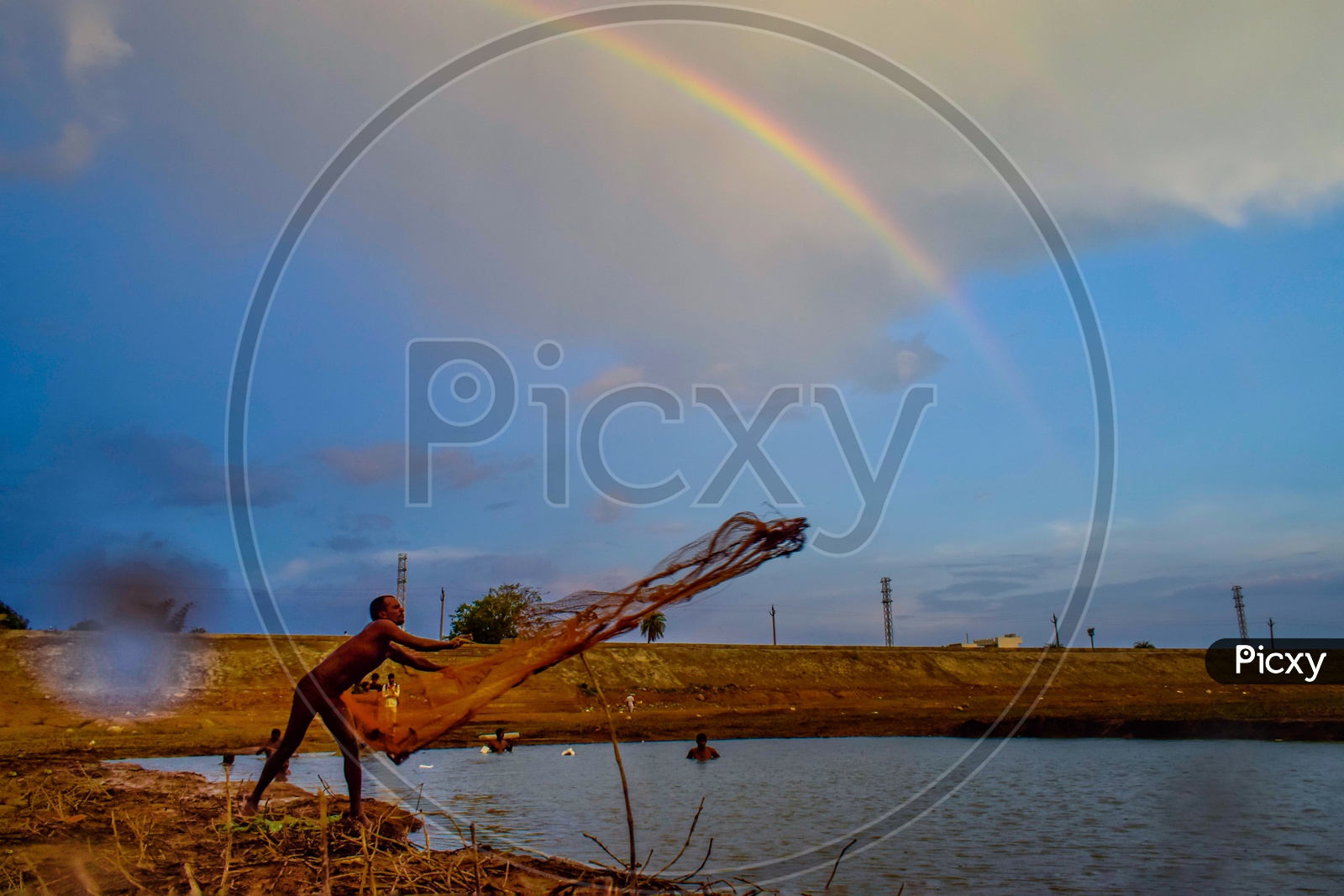 A Fisher Man Throwing Fishing Net into a Fishing Pond  With  Rainbow In Background