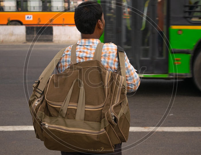 A man holding bag waiting for bus