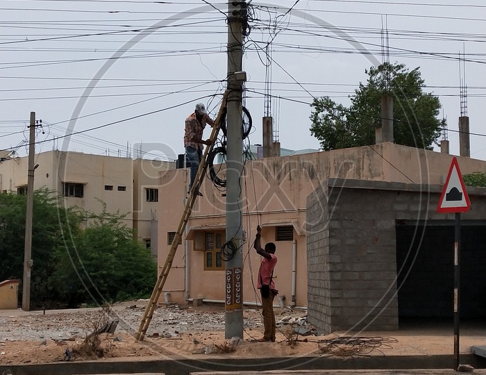 Two workers repairing the electric pole in afternoon