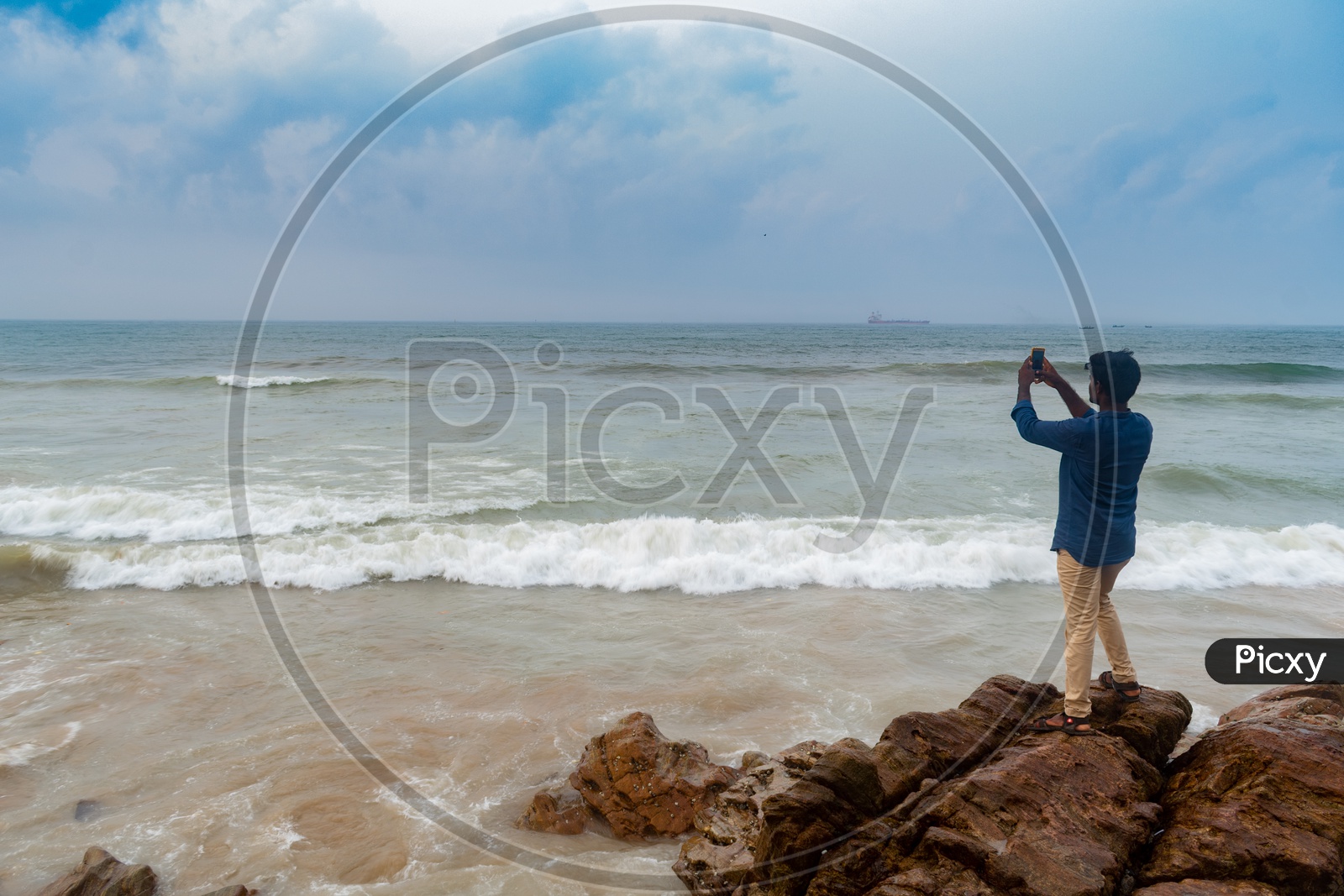Person/young man clicking a picture of Rama Krishna beach (R.K.Beach) standing on rocks at Vishakapatnam/Vizag.