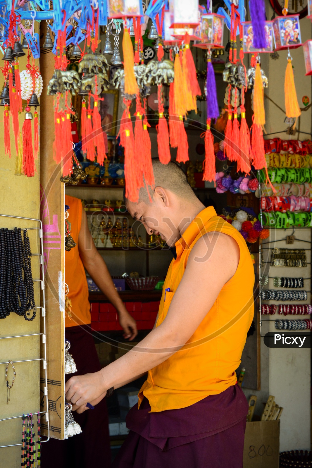 A buddhist monk checking out souvenirs at a shop.