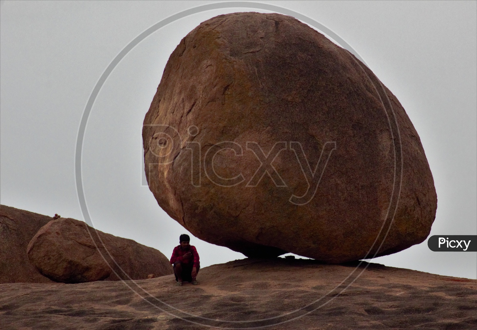 A Man Sitting Alone On A Rock hill And Using Mobile Phone