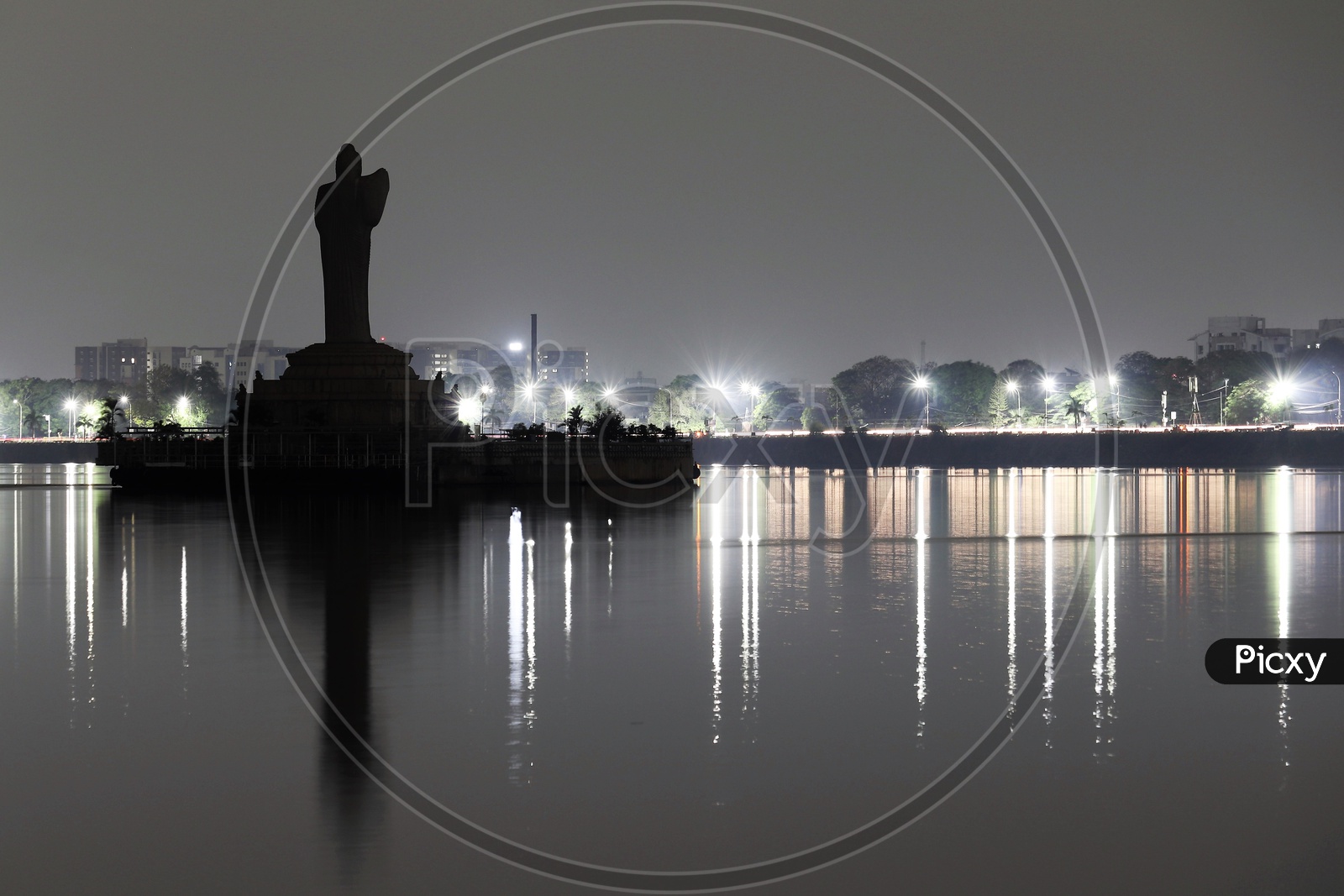 Silhouette Of Gautham Buddha Statue in Hussain Sagar Lake With Street Lights On Roads In Background