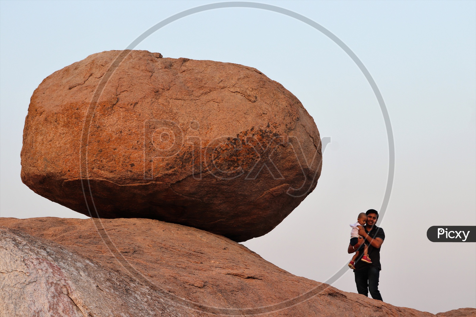 A Father Holding His Child In Arms on a Rock Hill