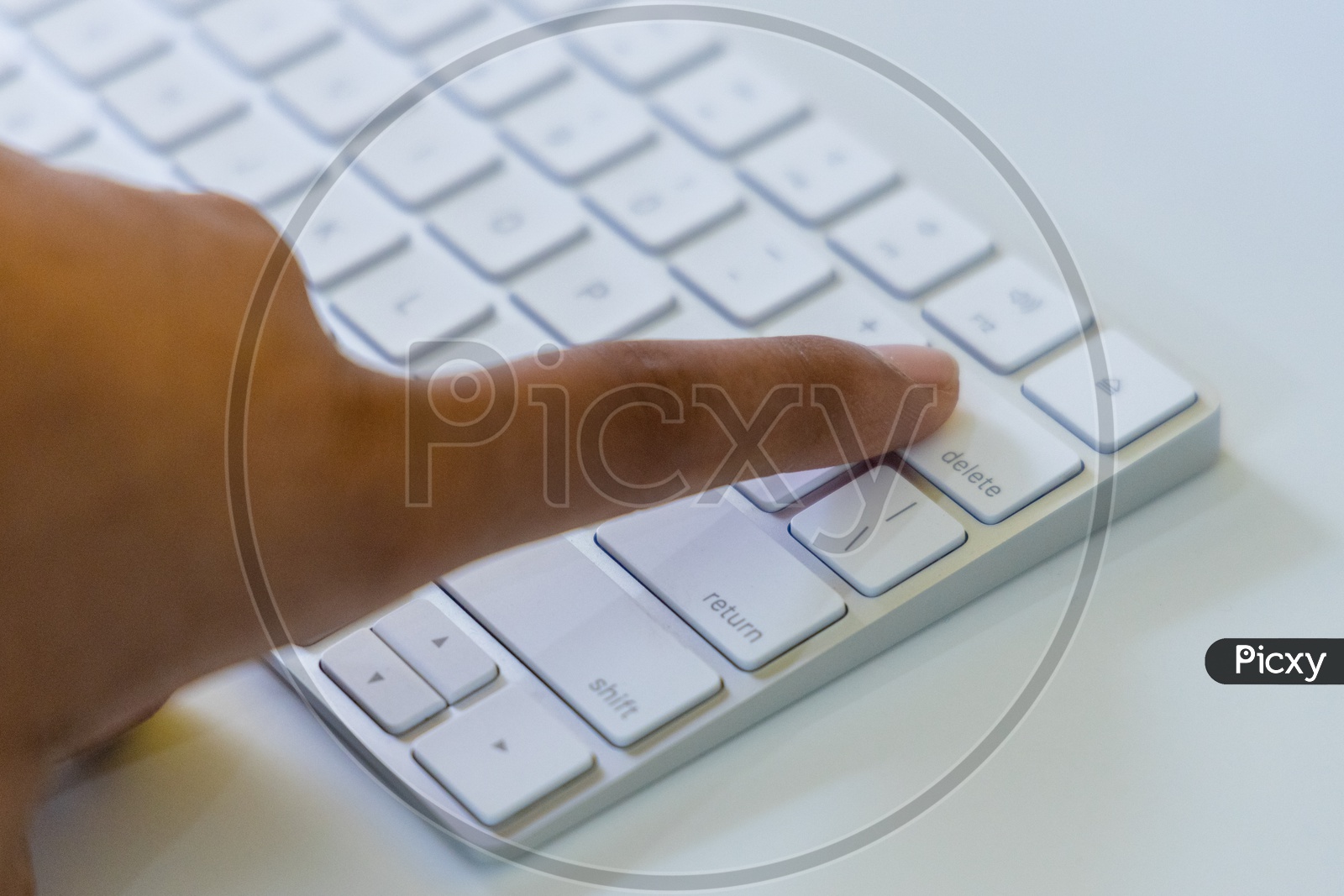 Man Finger Pressing  Delete Button or Key  on Keyboard Closeup On White Desk Background