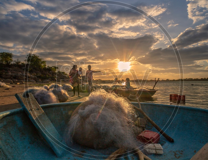 Fishing Nets And Coracle Boats On the bank Of A Lake With Sunset Sky In  Background