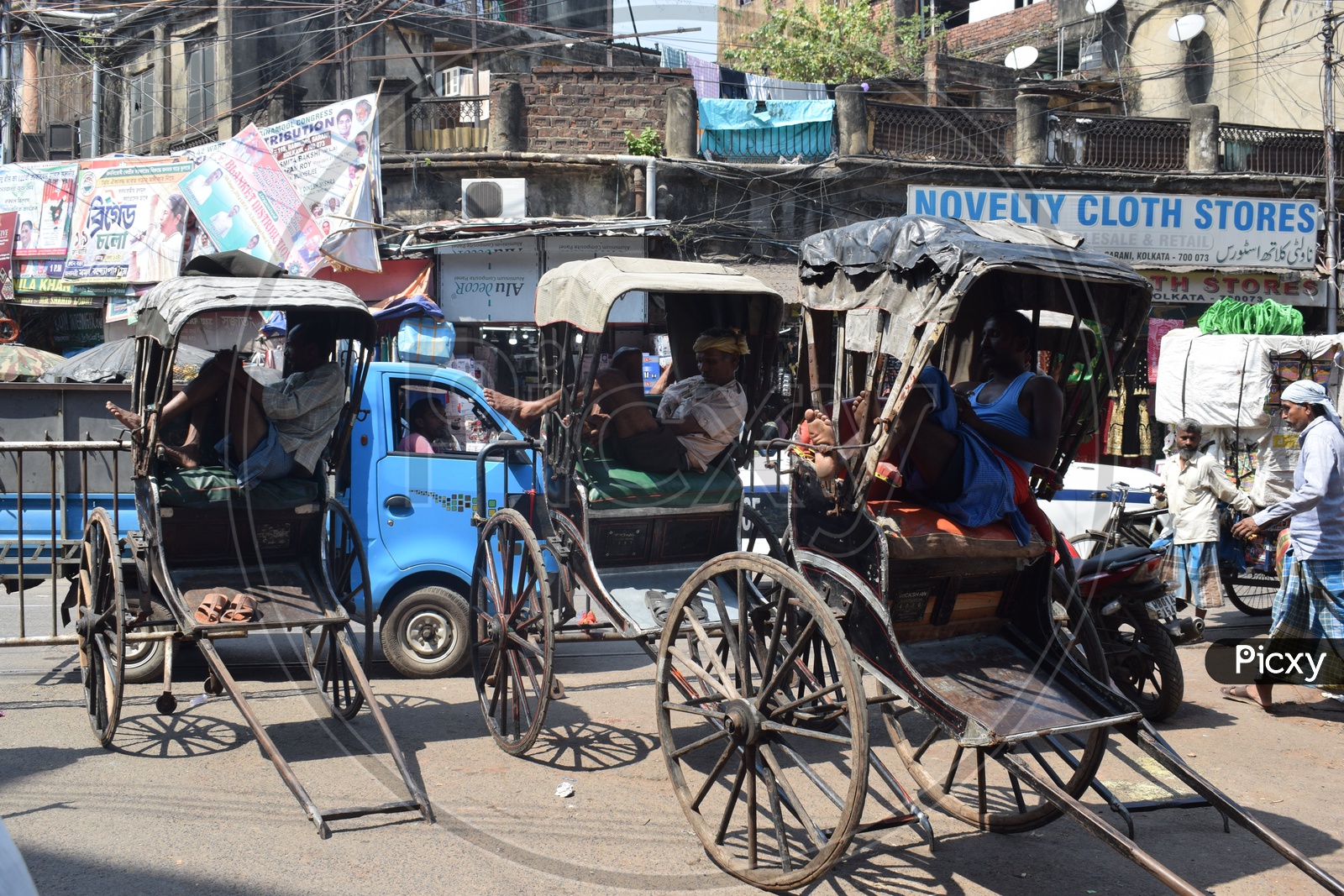 Rickshaw pullers taking a nap in a busy street