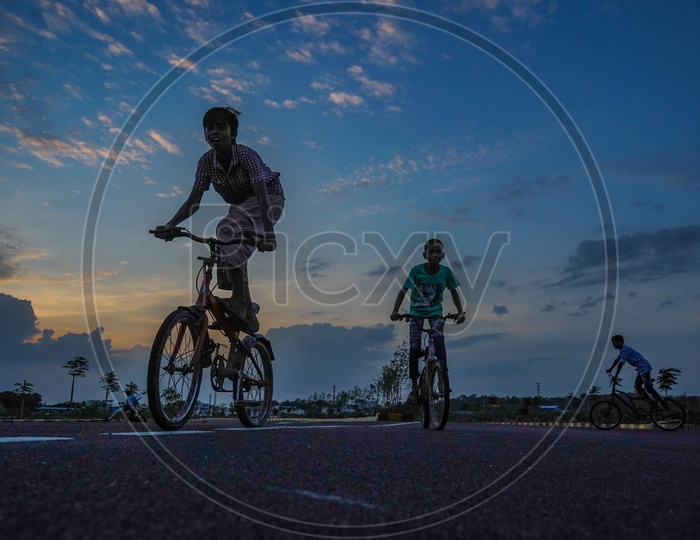 children cycling in cloudy evening