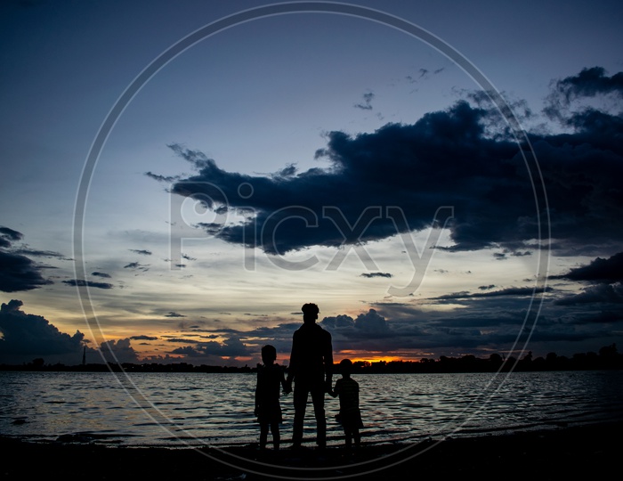 Silhouette Of a Man With Children At a Lake With  Blue Hour Sky In Background