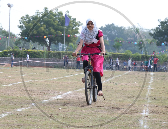 Indian Young School Girl Participating In a Cycle Race Competition In a School Sports Day Or Athletic Meet