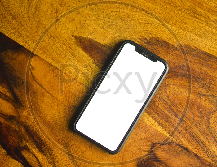 A Man Holding a Smartphone or Mobile  With Empty Space Or White Space For Advertising Purpose  on an Wooden Background