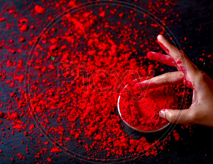 Sprinkling Holi Colours in Bowl  Hands Closeup   On an isolated Black Background