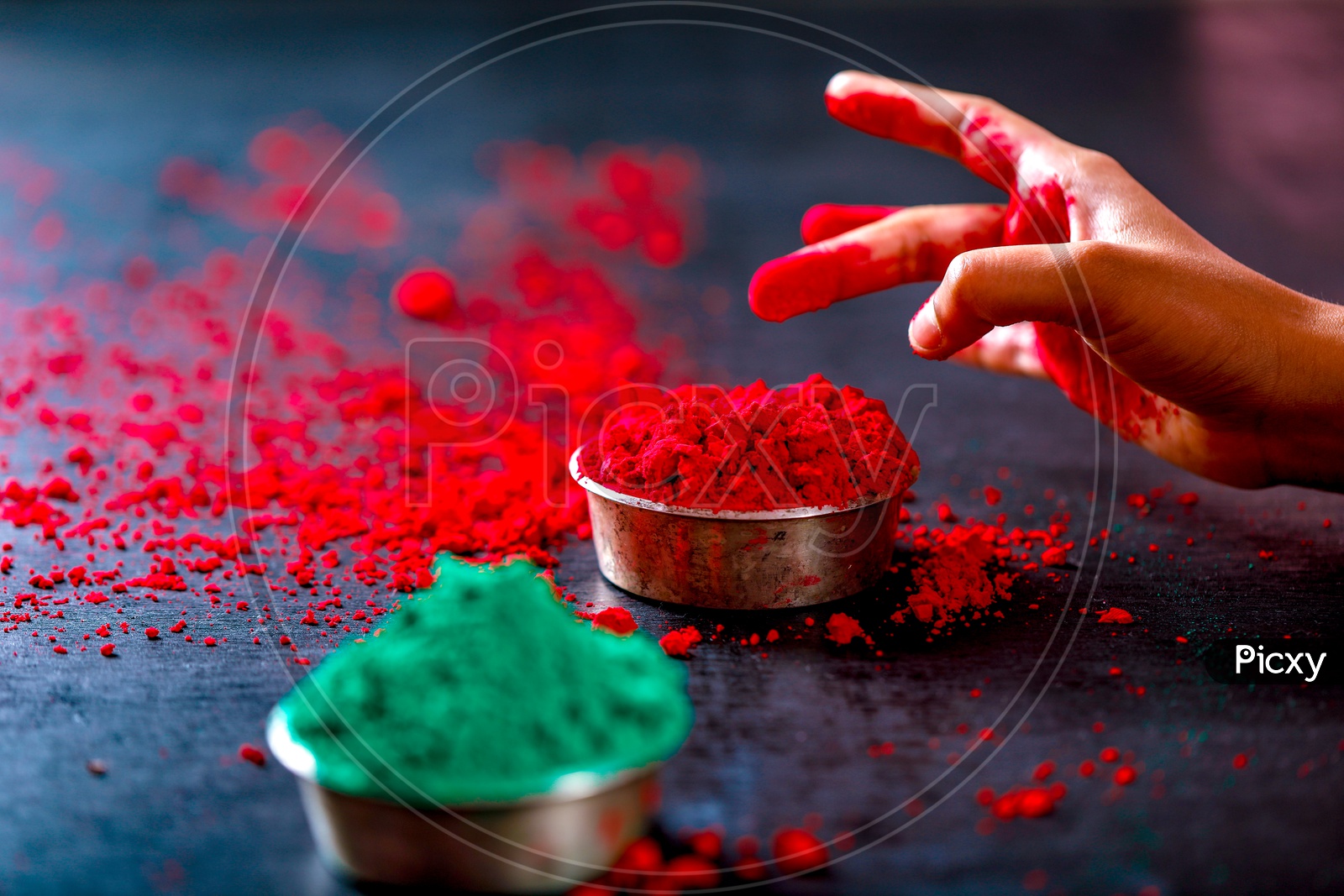 Sprinkling Holi Colours in Bowl  Hands Closeup   On an isolated Black Background