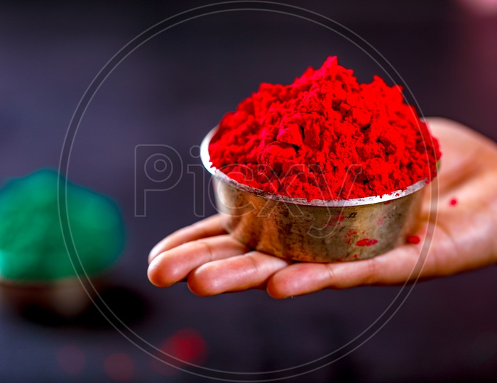 Holi Colours Bowl Holding in Hand Closeup  On an isolated Black Background