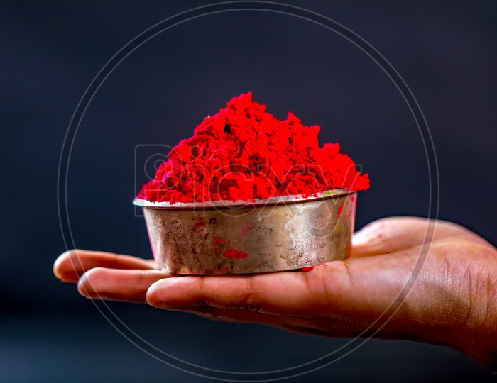 Holi Colours Bowl Holding in Hand Closeup  On an isolated Black Background