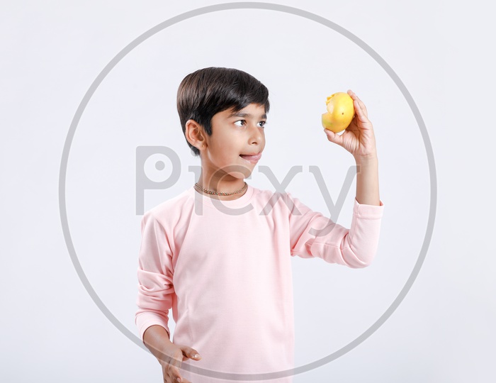 Indian Cute Boy  or Asian Boy or kid Holding Mango With an Expression On an Isolated White Background