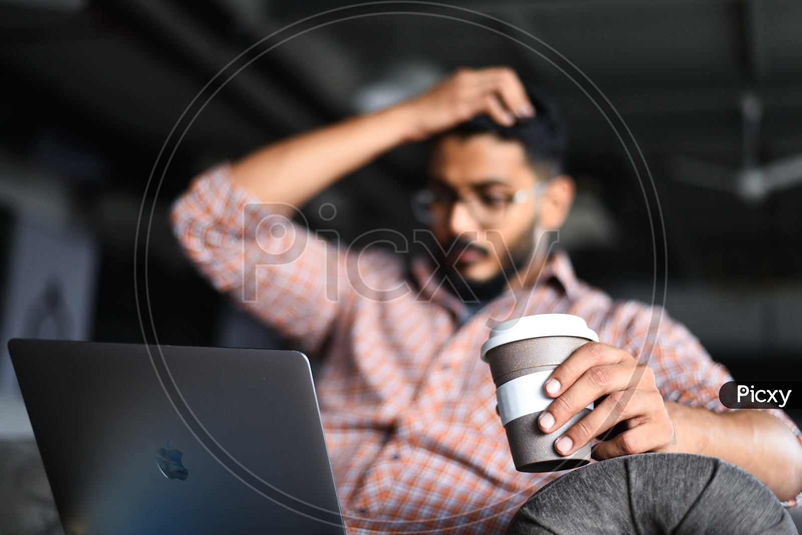 Frustrated Stressed Depressed Young Man Holding Head in Hands Working on Laptop With Coffee Cup   in Office Work Space