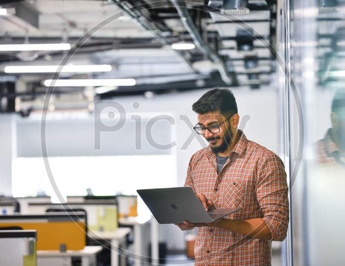 Young man or Indian man Happily Smiling Using Laptop in Working Space
