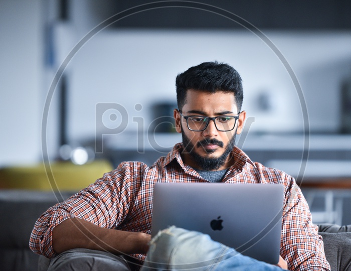 Focused Serious Working Young Man Or Indian Man On Laptop At  Work Space