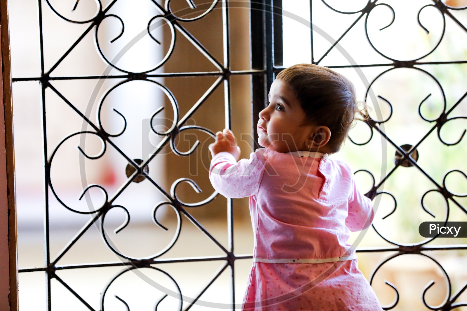 Cute Indian Baby Girl Standing at Grill Gate