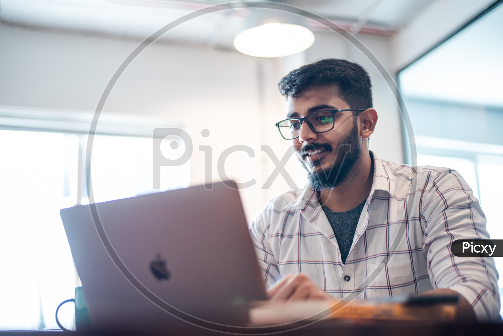 Indian professional Young Man Student employee  Happily Smiling Using Laptop in Working Space
