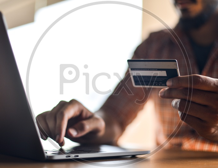 Online Payments Or Online Shopping  A Young Man Using Debit or Credit Card For Online Transaction or Payments in Laptop