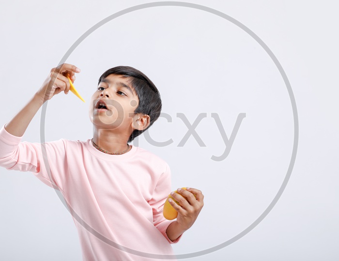 Indian Cute Boy  or Asian Boy or kid Enjoying Eating  Mango With an Expression On an Isolated White Background