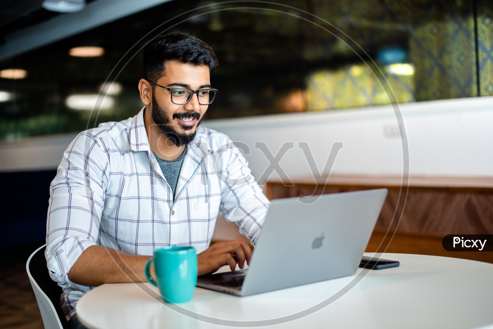 Student Young man  Indian young professional Employee Happily Smiling Using Laptop in Working Space